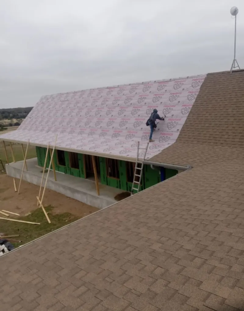 Worker preparing underlayment for a metal roof installation in Providence